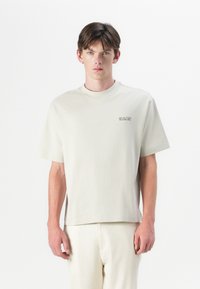 Helles beige T-Shirt mit kurzen Ärmeln und Rundhalsausschnitt, bestickt mit dem Logo "SELECTED" in dezentem Farbton. Weiches Baumwollmaterial, lockere Passform.