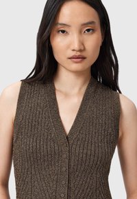 Brązowy sweter bez rękawów o żebrowanej fakturze, dekolcie w serek i zapięciu na guziki. Gładki materiał z metalowymi akcentami.