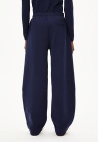 Marineblaue Sweatpants mit weitem Bein, elastischem Bund und Gesäßtasche, aus weichem Stoff mit lockerem, entspanntem Schnitt.