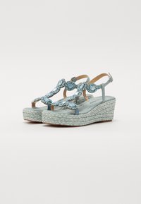 Sandales compensées bleu clair avec des accents en pierres décoratives, semelle en corde tissée, sangles de cheville ajustables et doublure en tissu doux.