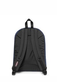 Svart ryggsäck med vadderad tyg, har justerbara axelremmar, ett handtag på toppen och en logotypetikett nära fäste för remmarna.