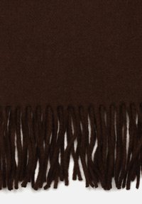 Brązowy wełniany szalik o miękkiej, textured powierzchni. Posiada długie frędzle wzdłuż jednej krawędzi, co nadaje przytulny i ciepły wygląd.