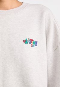 Light gray sweatshirt featuring a colorful embroidered "Vacation Club" logo on the left chest area. Soft texture and relaxed fit.