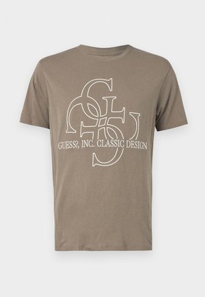 Tricou din bumbac maro, cu un design grafic alb, având litere interconectate și textul "GUESS?, INC. DESIGN CLASIC" în față.