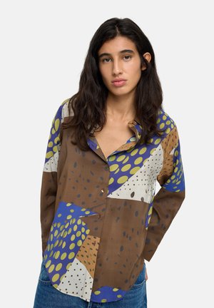 Koszula zapinana na guziki w odcieniach brązu, niebieskiego i zielonego, z nieregularnymi kropeczkami i geometrycznymi wzorami na miękkim materiale.
