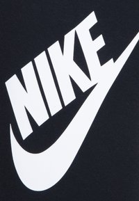 Black fabric T-shirt featuring a large white "NIKE" logo and swoosh design. Soft texture with a classic crew neck style.
