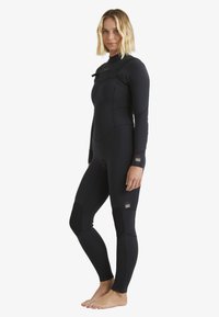 Wetsuit in black neoprene with long sleeves, fitted design, knee pads, and front zipper. Accents on wrists feature brand logo.