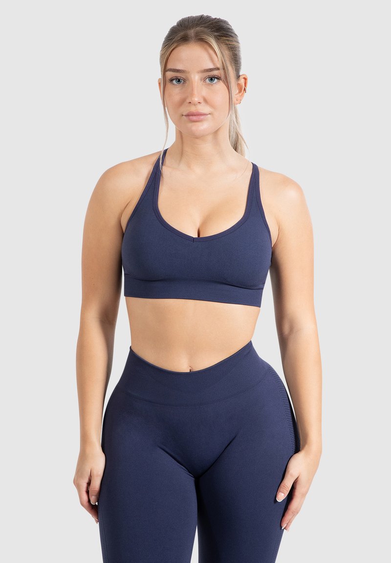 Sujetador deportivo azul marino y leggings de cintura alta, hechos de tela elástica. Presenta tirantes entrecruzados y un diseño sin costuras para mayor comodidad.
