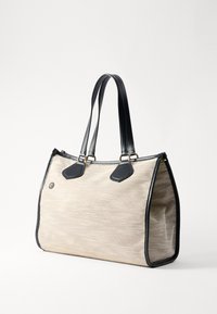 Béžová látková taška s černými koženými akcenty a rukojeťmi, se dvěma trojúhelníkovými černými koženými detaily a zlatými kovovými prvky.