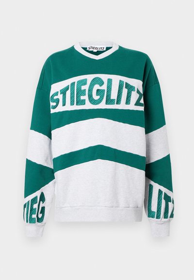 Zelená a šedá oversized mikina s výstřihem do V, na které je v tučných, texturovaných písmenech napsáno "STIEGLITZ" na hrudi a rukávech.