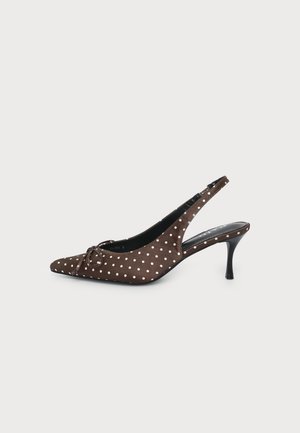 Chaussure à talon kitten marron avec bride arrière, pois blancs et petit nœud sur l’orteil pointu, vue de côté sur fond blanc.