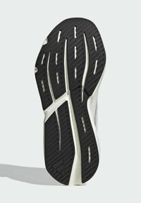 Suela de goma negra con profundas ranuras y entresuela blanca. El diseño presenta patrones de banda de rodadura únicos para tracción y flexibilidad.
