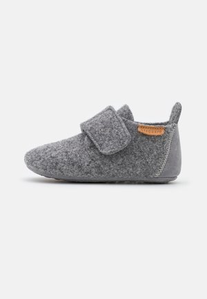 Chaussure bébé en feutre gris avec large bride velcro, semelle souple et languette au talon, présentée sur un fond blanc uni.