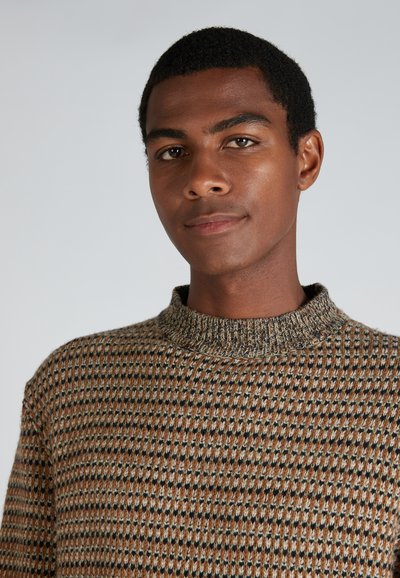 Trui gebreid met een hoge kraag, met een textuurpatroon in bruin, beige en marineblauw. Materiaal lijkt zacht en heeft een gemiddelde dikte.