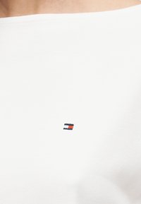 Λευκό βαμβακερό πουκάμισο με μικρό, κεντητό λογότυπο σε ναυτικό μπλε, κόκκινο και λευκό. Διαθέτει φαρδιά λαιμόκοψη με λεία υφή.