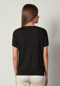 Svart kortärmad topp i mjukt, lätt material med rundad halsringning och en något figursydd midja.