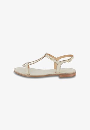 Sandalo piatto beige con design T-strap, cinturino alla caviglia regolabile e tomaia in pelle liscia con suola marrone chiaro.