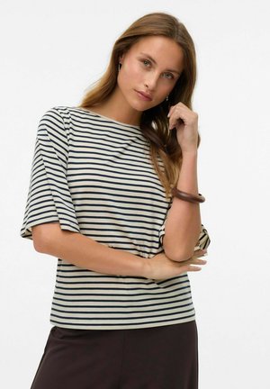 T-shirt rayé en crème et bleu marine, avec un col rond et des manches courtes, associé à un pantalon large sombre et un bracelet marron.