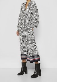 Svartvit mönstrad klänning med långa ärmar, insvängd midja och randig fåll. Matchad med svarta ankelskor med blockklack.