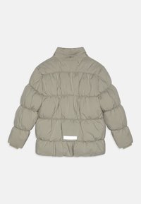 Uppblåsbar jacka i ljusgrått, med ett kviltat mönster och insamlade sektioner, en hög krage och en liten vit etikett på baksidan.