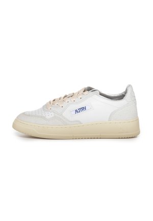 Sneaker en cuir blanc avec des accents beiges, des détails en suède texturé, une semelle crème et un logo bleu proéminent sur le côté. Dispose de lacets plats.