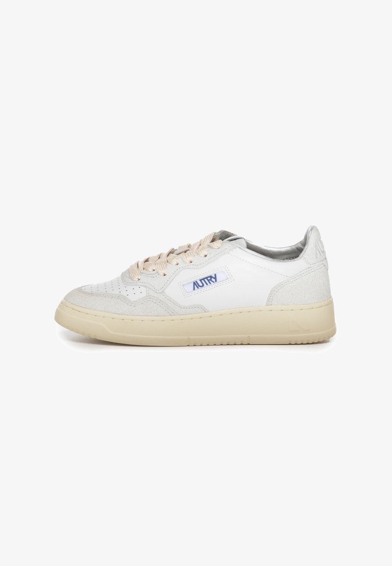 Hvide lædersneakers med beige accenter, teksturerede ruskindsdetaljer, cremefarvet sål og et fremtrædende blåt logo på siden. Har flade snørebånd.