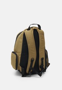 Khaki plecak z czarnymi akcentami, wyściełanym siatkowym tyłem, regulowanymi paskami i boczną kieszenią, o zestalonym kształcie i trwałym materiale.