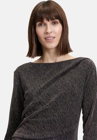 Maglietta nera in maglia con un design arricciato sulla parte anteriore, caratterizzata da una scollatura ampia a barca e una finitura strutturata con fili metallici.