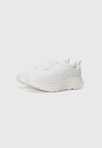 Baskets de course blanches avec des dessus texturés, des semelles rembourrées et un logo prominent. Présente un design à lacets et un matériau doux et flexible.