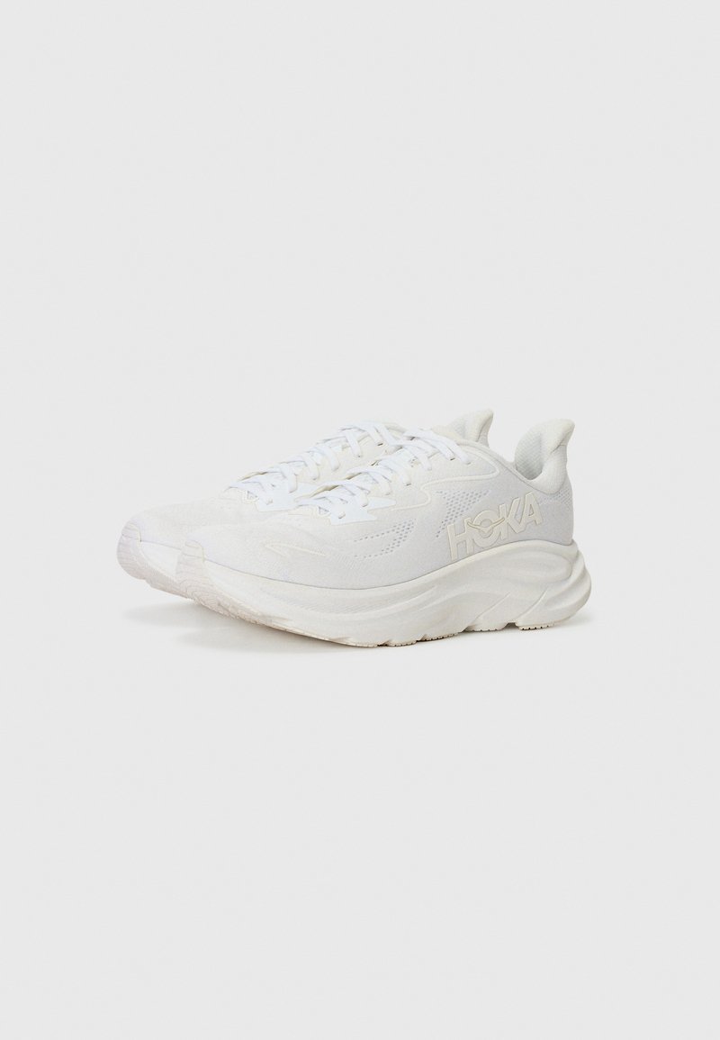 White running shoes with textured uppers, cushioned soles, and a prominent logo. Features lace-up design and soft, flexible material.