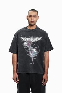Sort oversized T-shirt med korte ærmer, der har et grafisk design af en rose med kæde-detaljer, sat op imod en slidt stofstruktur.