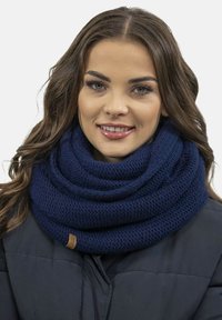 Granatowy, dziany szalik w formie infinity z teksturowanym wzorem, posiadający złożony design i małą brązową etykietę akcentującą. Noszony na ciemnym płaszczu.