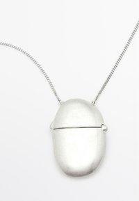 Zilveren metalen ketting met een afgeronde, pilvormige hanger met een naad en een klein rond detail aan de bovenkant. De ketting is stijlvol en eenvoudig.