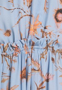 Svetle modré šaty s květinovým vzorem v oranžové a hnědé barvě. Mají nadýchaný pas a měkkou, strukturovanou látku pro pohodlí.