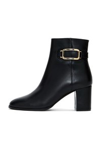 Botte de cheville en cuir noir avec un bout carré, un talon bloc de hauteur moyenne et un accent de boucle dorée sur le côté extérieur. Texture lisse.
