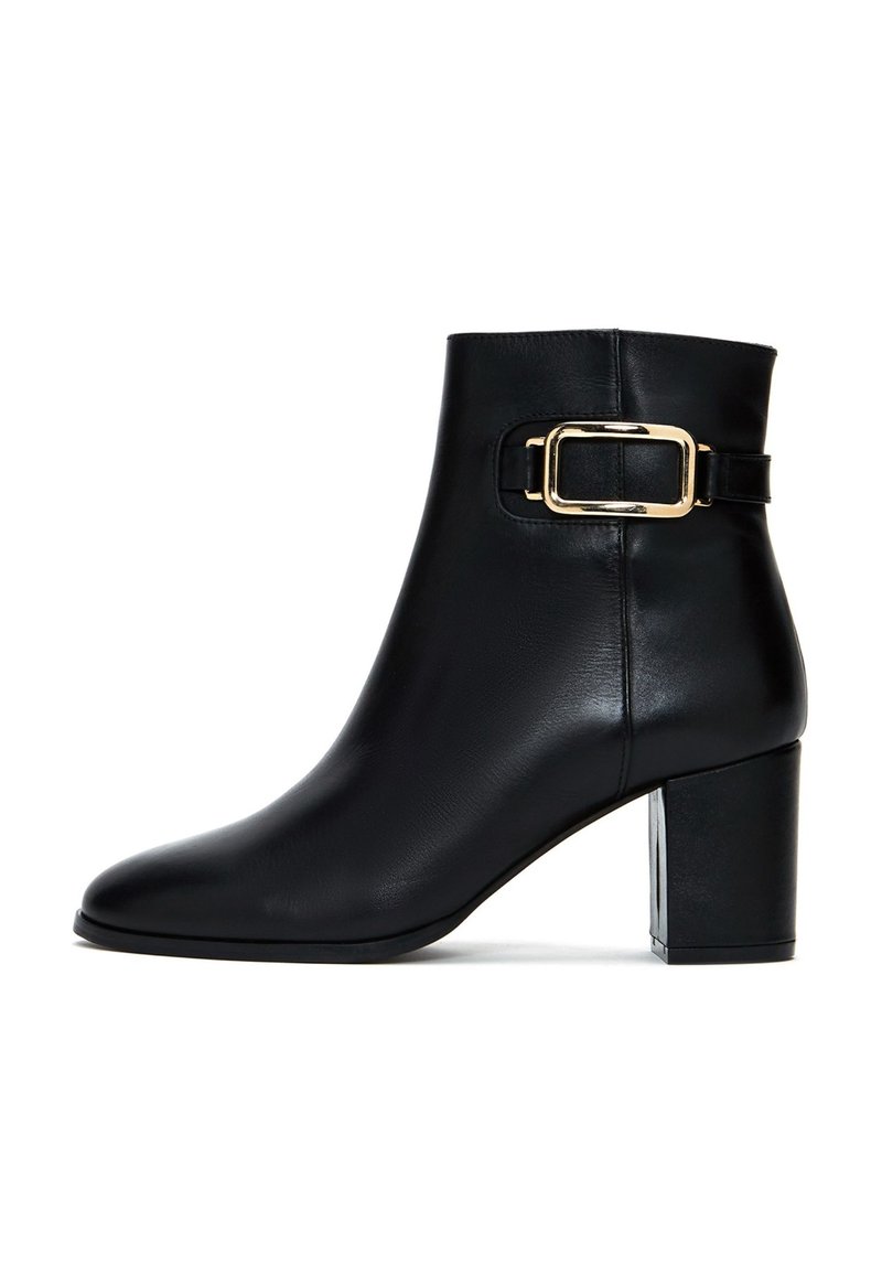 Botte de cheville en cuir noir avec un bout carré, un talon bloc de hauteur moyenne et un accent de boucle dorée sur le côté extérieur. Texture lisse.