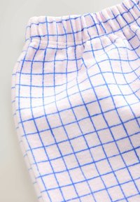 Ružová tkanina s textúrovaným povrchom s mriežkovým vzorom modrých línií. Pás je elastický pre pohodlie.