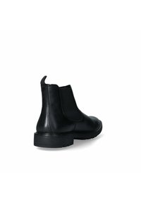 Stivali alla caviglia neri in pelle con pannelli laterali elasticizzati, punta arrotondata e suola in gomma testurizzata. Presentano cuciture minime e un piccolo inserto per il tallone.