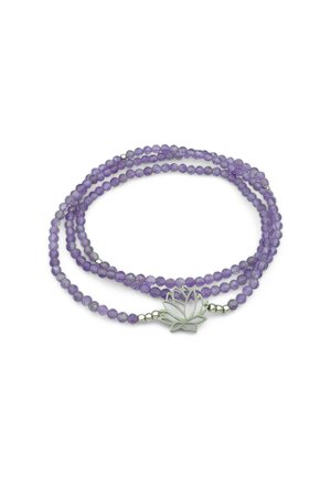 Collana di perline viola con più fili e un ciondolo a forma di fiore di loto in argento al centro, posata su uno sfondo bianco.