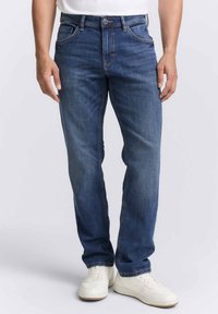 Jeans in denim blu con un taglio dritto classico, design a cinque tasche e leggere sfumature, abbinati a sneakers bianche.