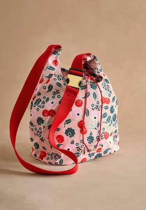Drawstring bag in pink fabric with floral and cherry patterns. Features a red adjustable strap and a gold-tone buckle for closure.