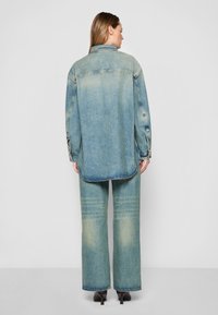 Camicia di denim con una lavatura blu chiaro sbiadita, maniche lunghe e polsini con due bottoni, abbinata a pantaloni in denim a palazzo coordinati.