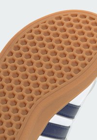 Suela de zapato de goma con un patrón de panal, en color beige y con agarre texturizado. Incluye un borde liso y elementos de diseño en capas.