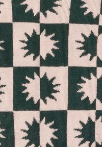Stricktyg med ett grön och krämfärgad schackrutemönster med solstrålemotiv i växelvis rutor. Mjuk textur, geometrisk design.