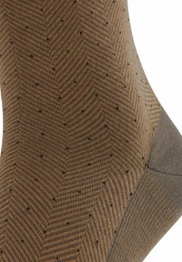 Brown and gray herringbone-patterned sock with small black dots, featuring a reinforced toe and heel. Smooth texture, mid-calf length.