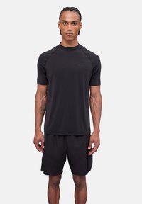 Camiseta negra de manga corta atlética con cuello redondo, hecha de un tejido que absorbe la humedad, combinada con pantalones cortos negros a juego.