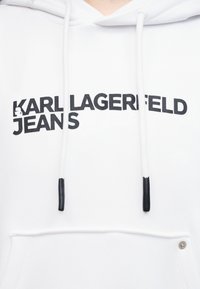 Λευκό φούτερ με κουκούλα με μαύρο κείμενο "KARL LAGERFELD JEANS" και μικρό λογότυπο στο στήθος, με κορδόνια με μαύρες άκρες και τσέπη μπροστά.