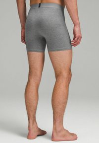 Graue Boxershorts aus weichem Stoff mit einem glatten Bund und einer engen Passform, die bis zur Mitte des Oberschenkels reichen. Ohne bemerkenswerte Muster oder Akzente.