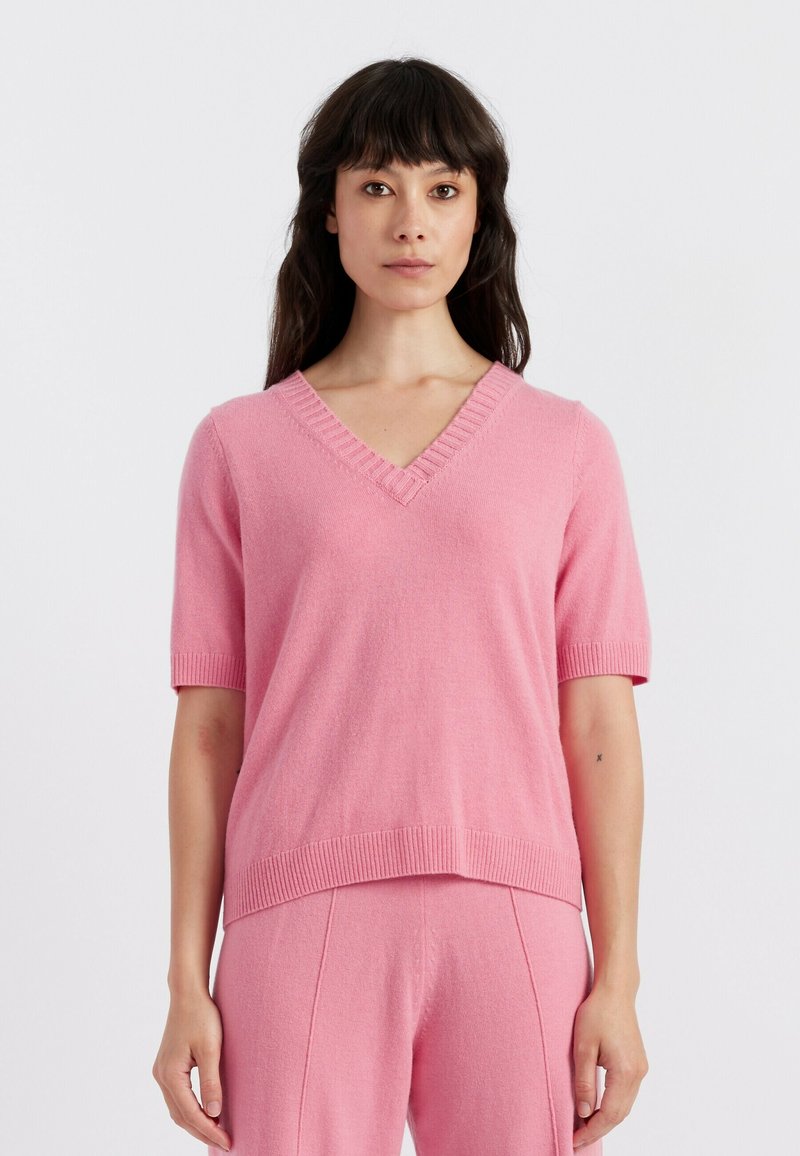 Maglione a maniche corte con scollatura a V in morbido maglione rosa, caratterizzato da polsini e orlo a coste, offre una vestibilità rilassata e una texture liscia.