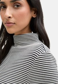 Pull à col roulé rayé en noir et blanc, présentant un design ajusté avec une texture douce et un col haut.